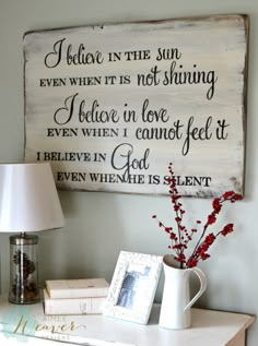 a white table with a lamp and some books on it, next to a sign that says love how about you? i believe in the sun even when it is not shining