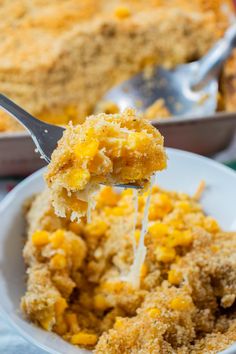 a spoonful of food is being lifted from a white bowl with cornbread casserole