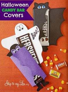 halloween candy bar covers with candy and candies on an orange tablecloth, next to two bats