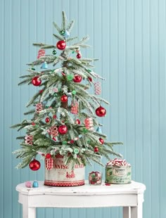 a small christmas tree sitting on top of a white table next to a can filled with candy