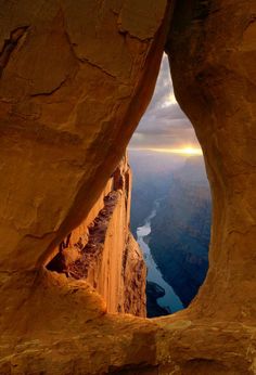 an open window in the side of a cliff overlooking a body of water and mountains