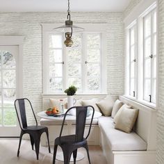 two chairs and a table in a small room with white brick wallpaper on the walls