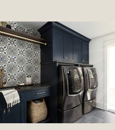 a washer and dryer are in the middle of a room with blue cabinets