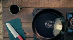 a pan with some butter on top of it next to a knife and a cup