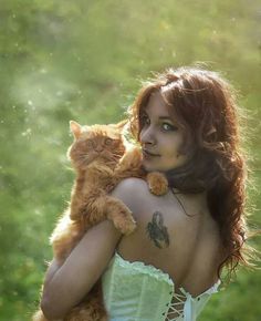 a woman in a corset holding an orange cat on her shoulder and looking at the camera