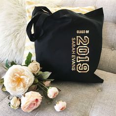 a black bag sitting on top of a couch next to some white and pink flowers