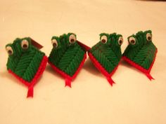 three little green hats with googly eyes and red trim on them, sitting next to each other