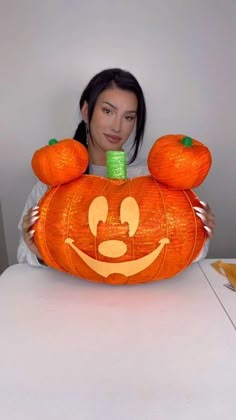 a woman holding up a pumpkin shaped like mickey mouse