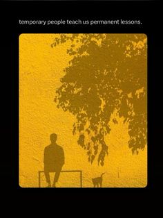 a man sitting on top of a bench next to a tree and a yellow wall