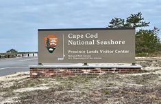 a sign for cape god national seashore in front of a road with trees and bushes