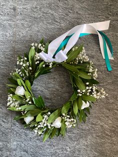 a wreath with white flowers and baby's breath tied to it on the ground