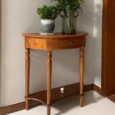 a wooden table with two potted plants sitting on it's shelf next to a mirror