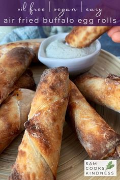 an egg roll is on a plate with dipping sauce in the middle and other food items around it