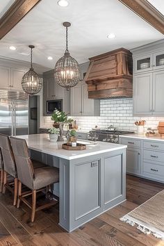 a kitchen with gray cabinets and white counter tops, wooden flooring and chandeliers