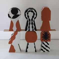 three wooden figures are stacked on top of each other, one is orange and the other is black