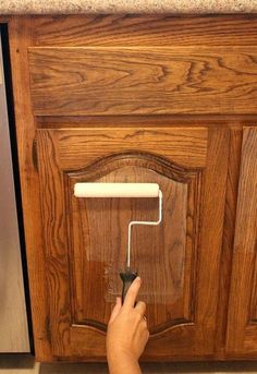 a person using a paint roller to paint cabinet doors with text overlay that reads the hottest new way to paint cabinets