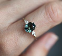 a woman's hand holding an engagement ring with a blue and white diamond in it