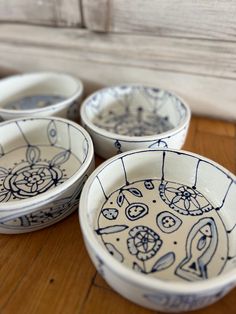 four bowls with designs on them sitting on a table