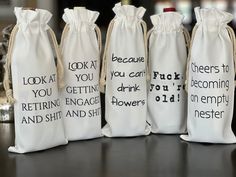 four wine bags with words on them sitting on a table next to a candle holder