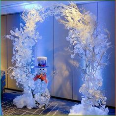 two snowmen are standing next to each other in front of a blue wall with frosty branches