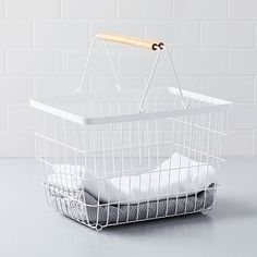 a white basket with folded towels hanging from the handle on a gray countertop next to a brick wall