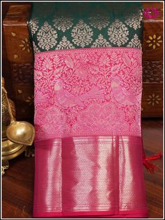 A Kanchipuram silk saree in an enchanting green hue highlights an ornate floral motifs on the body. The contrasting pinkish-red pallu showcases brocade designs, margined by lively parrot and peacock along with floral patterns provide a sense of natural beauty. The lush green shade represents freshness and vitality, while the intricate patterns add an element of traditional opulence. This saree incorporates bold pinkish-red double border. The cross striped border at the bottom complements the abo Pure Silk Sarees, Handloom Saree, Lush Green, Blouse Piece, Mulberry Silk, Floral Motif, Shades Of Green, Silk Sarees, Floral Pattern