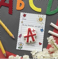 a note with the letter a on it next to pencils and flowers