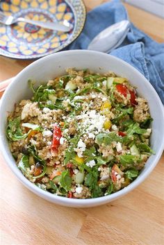 a white bowl filled with salad on top of a wooden table next to a plate