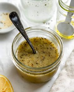 a spoon in a jar filled with liquid next to some lemons and other ingredients