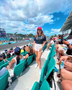 a woman is standing in the stands at a race track while people watch from behind her