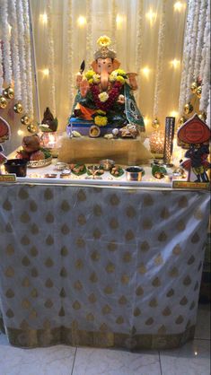 an elephant statue sitting on top of a table covered in flowers and decorations with lights behind it