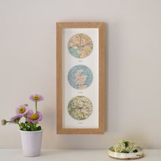 three framed maps sitting on top of a white table next to a potted plant