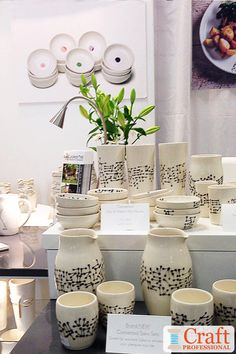 a table topped with lots of white vases filled with flowers next to each other