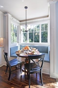 a dining room table with two chairs and a bench in front of a bay window