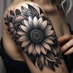 a woman's arm with a black and white flower tattoo on the left shoulder