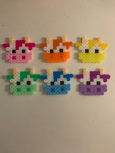 six pieces of plastic bead art on a white surface, each with different colors and shapes