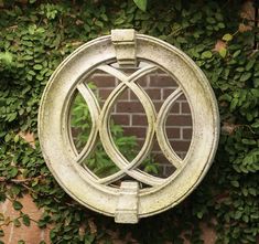 an old mirror hanging on the side of a brick wall with ivy growing around it