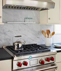 a stove top oven sitting inside of a kitchen next to a counter with utensils on it