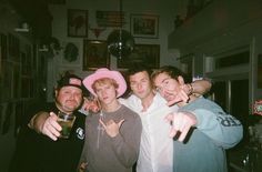 a group of young men standing next to each other in a room with pictures on the wall