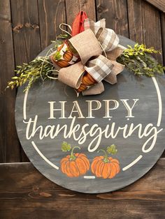 a sign that says happy thanksgiving hanging on the side of a wooden fence with pumpkins