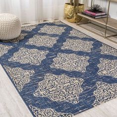 a blue area rug with an intricate design on the bottom and sides, in front of a window