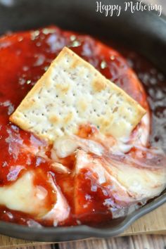 sweet and spicy baked brie with crackers in a skillet, ready to be eaten