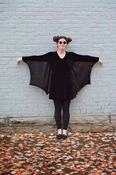 a woman standing in front of a white brick wall with her arms spread wide out