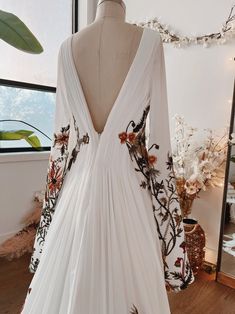 the back of a wedding dress on display in front of a window with flowers and leaves