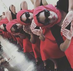 a group of women in red dresses standing next to each other with their hands together