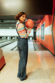 a woman holding a bowling ball in her right hand while standing on a bowling alley