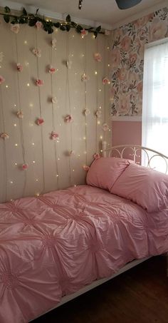 a bedroom with pink bedding and lights on the wall