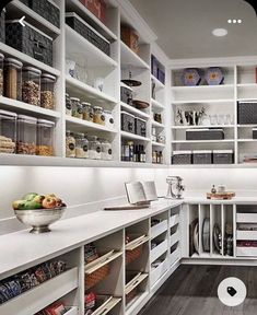 a kitchen with white cabinets and shelves filled with food