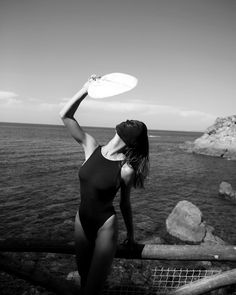 a woman in a bathing suit holding a frisbee near the water's edge