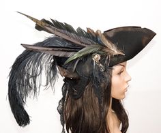 a woman wearing a black hat with feathers on it